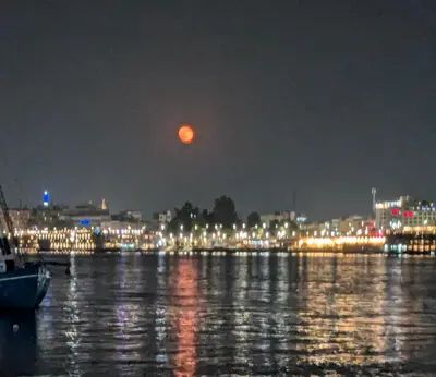 a full moon rising over a city at night at Al Ramla Guest House in Luxor