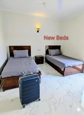 a room with two beds and a suitcase on the floor at Al Ramla Guest House in Luxor