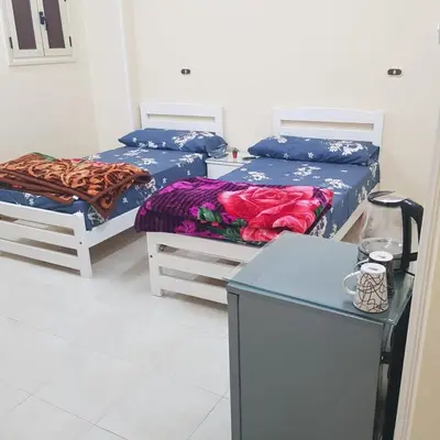 a room with two beds and a table and a table at Sweet Home 5 Open 24 Hour in Hurghada