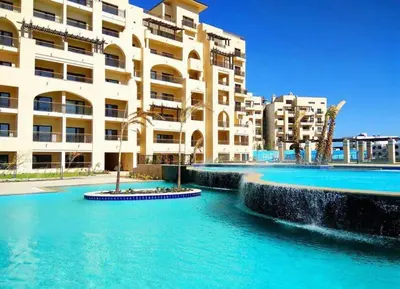 a large building with blue water in front of it at AlDau Hights one Bedroom Elegante Apartment 10201 in Hurghada