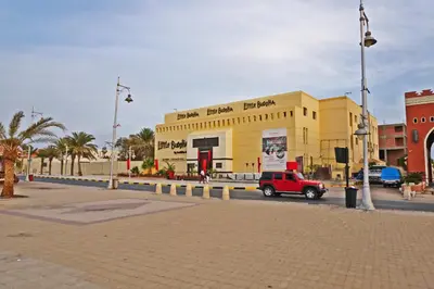 a yellow building with a red truck parked in front of it at The Touristic Promenade Apartment in Hurghada