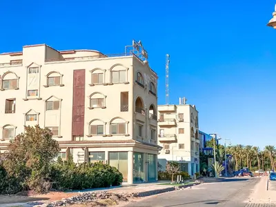 a tall white building on the side of a street at The Touristic Promenade Apartment in Hurghada