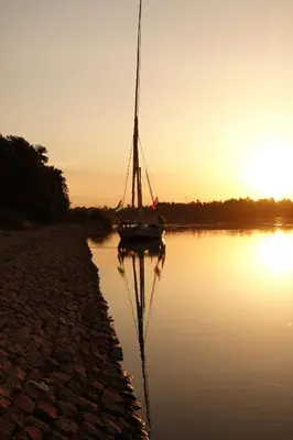 a sail boat sitting in the water at sunset at JJ Jamaica Felucca in Aswan