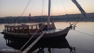 a boat is docked in the water at a dock at JJ Jamaica Felucca in Aswan