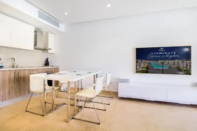 a kitchen with a table and chairs and a tv at Ollystays Mangroovy 2 BR Beach and Pool Free access in Hurghada