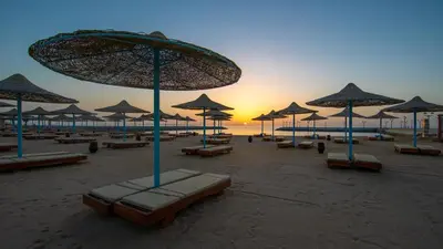 a beach with chairs and umbrellas and the ocean at New Eagles Aqua Park Resort in Hurghada