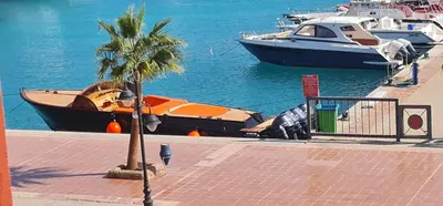 a palm tree and a boat in the water at Amazing 2 bedrooms' Flat Marina El-Hurghadah in Hurghada