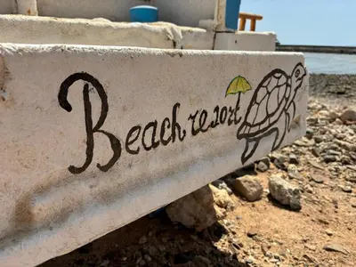a sign for a beach house with an umbrella on it at Turtles Beach Resort - Sea View in Hurghada