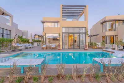 a villa with a swimming pool in front of a house at La Casa de Playa Tawila on Island 4BR Private with Heated Pool in Hurghada