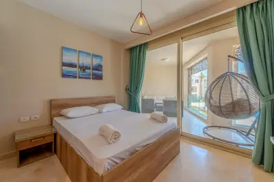 a bedroom with a bed and a large window at Mangroovy 3BR Apartment Private Beach & Pool View in Hurghada