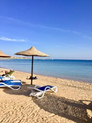 two lounge chairs and an umbrella on a beach at سهل حشيش in Hurghada