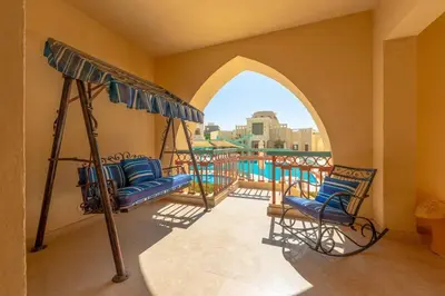 a balcony with two chairs and a swing at Marina Mosaique 1 BR Apartment with Pool view in Hurghada