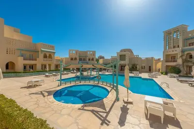 a large swimming pool in a courtyard with buildings at Marina Mosaique 1 BR Apartment with Pool view in Hurghada