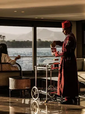 a woman is standing next to a cart on a boat at Historia The Boutique Hotel Nile Cruise - Every Monday from Luxor for 04 & 07 Nights - Every Friday From Aswan for 03 & 07 Nights in Luxor