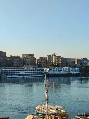 a boat sitting in the water with a cruise ship at Jamaica Guest House in Aswan