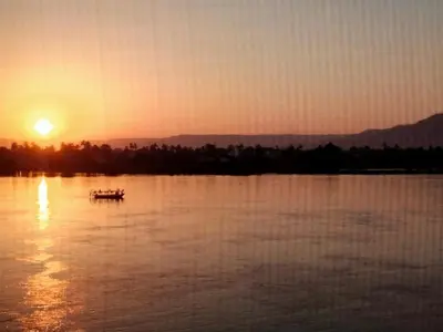 a boat on the water with the sunset in the background at Nile queen Apartments for Rent in Luxor