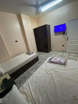 a room with two beds and a flat screen tv at ALRahman Building in Aswan