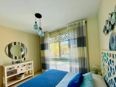 a bedroom with a bed and a mirror and a window at Kitesurfer Shared House, Pool View & Beach Access in Hurghada