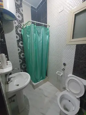 a bathroom with a toilet and a green shower curtain at Abeer suites 2 in Hurghada