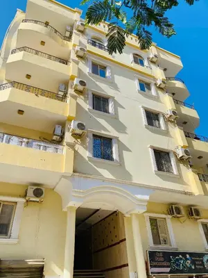 a tall white building with windows and a tree at RITA HOUSE SEA VIEW. Hurghada center in Hurghada