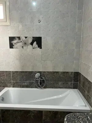 a bath tub in a bathroom with a picture of flowers at Valley Of The Kings House in Luxor