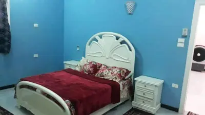 a bedroom with a bed with a blue wall at Bob Marley Guest House in Luxor