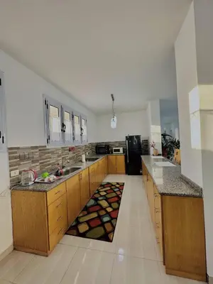 a large kitchen with wooden cabinets and a black refrigerator at Luxor Rose Villa in Luxor