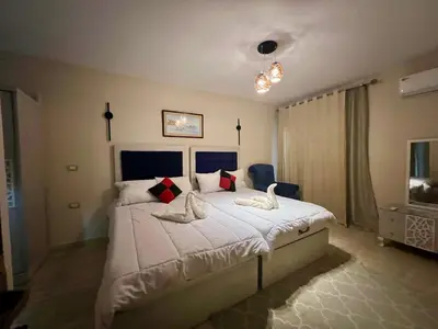a bedroom with a large bed with white sheets and red pillows at Villa KUBA luxury private pool Hurghada in Hurghada