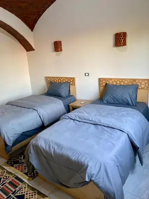two beds in a room with blue sheets at Tasneem Palace in Luxor