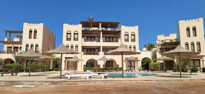 a large building with a pool and tables and umbrellas at El Gouna Fanadir Lagoon 2-Bedroom Pool and Lagoon View Sleeps 4 Persons, Close to Abu Tig Marina, Mangroovy, and Kite Centers in El Gouna
