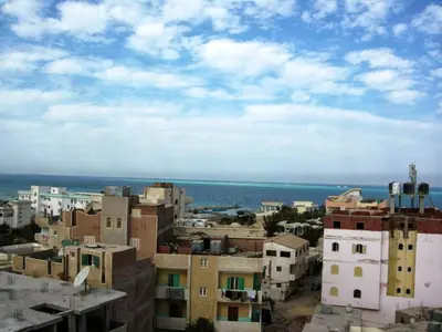 a city with buildings and the ocean in the background at Luxor Hotel Hurghada in Hurghada