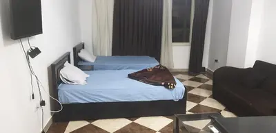 two beds in a room with a television and a couch at Studio pool view next to the Marina,Sheraton Plaza 320 in Hurghada