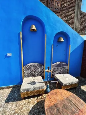two chairs and a table in front of a blue wall at Golden palace Nile view - Appartment in Luxor