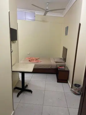a small room with a bed and a desk in it at Makkah Hotel in Qena