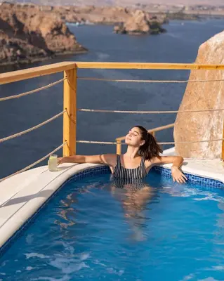 a woman laying in a swimming pool on a cruise ship at Benben by Dhara Hotels - Adults Only in Aswan