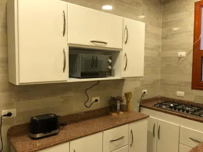 a kitchen with white cabinets and a microwave on a counter at Sphinx Luxor Apartment in Luxor