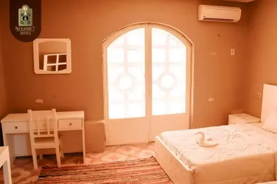 a bedroom with a bed and a desk and a window at Sekhmet Retreat Centre in Luxor