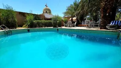 a swimming pool with blue water in a yard at Sekhmet Retreat Centre in Luxor