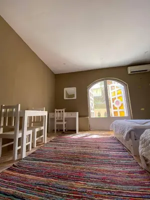 a bedroom with two beds and a large rug at Sekhmet Retreat Centre in Luxor