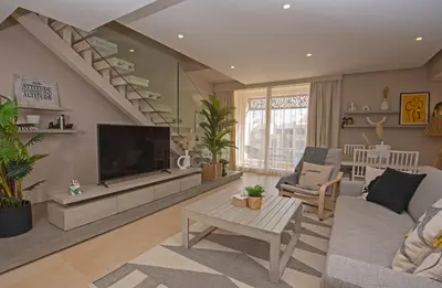 a living room with a couch and a television and stairs at A Stunning Seaview Penthouse; 3bedrooms + nanny in Hurghada