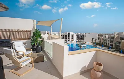 a balcony with two chairs and a swimming pool at A Stunning Seaview Penthouse; 3bedrooms + nanny in Hurghada