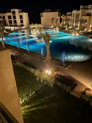 a large swimming pool at night with lights at A Stunning Seaview Penthouse; 3bedrooms + nanny in Hurghada