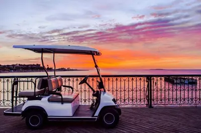 a golf cart parked on a pier with a sunset at JWE Residence - Quality experience near Red Sea in Hurghada