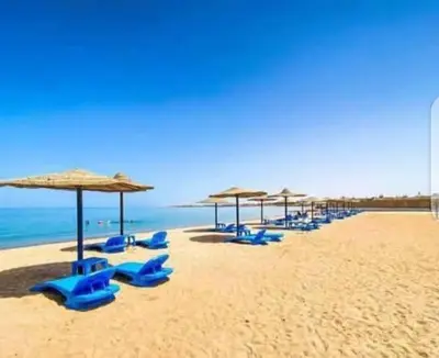 a group of blue chairs and umbrellas on a beach at Cecilia Resort Chalets- Hurghada in Hurghada