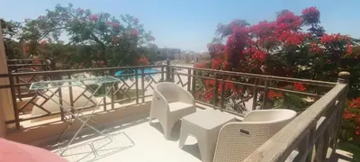 a balcony with white chairs and red flowers at The view studio in Hurghada