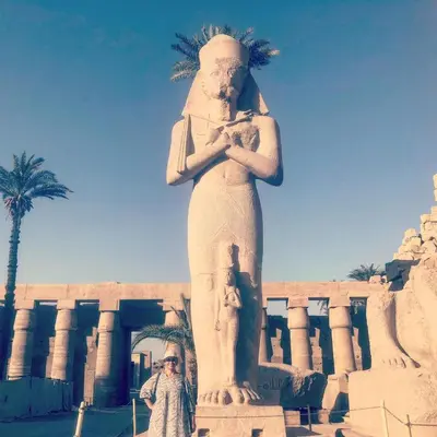 a man standing next to a statue in front of a building at One Love Guesthouse & Restaurant in Luxor