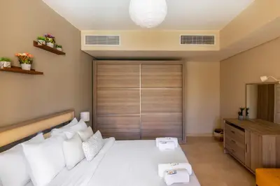 a bedroom with a large white bed and a wooden door at Jazzy 1BDR w Outdoor Pool View Terrace Free Pool & Beach Access in Hurghada