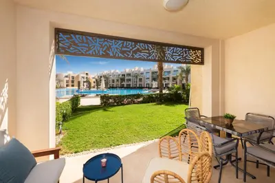 a patio with a table and chairs and a view of a yard at Elegant & Edgy 2 BR w Beach & Pool Mangroovy in Hurghada