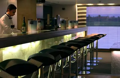a man standing at a bar with a row of chairs at Le Fayan Nile Cruise - Every Monday from Luxor for 4 & 7 Nights, and every Friday from Aswan for 3 & 7 Nights in Luxor