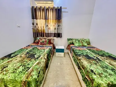two beds in a small room with curtains at Cozy Apartment in Qadd el-Barûd
